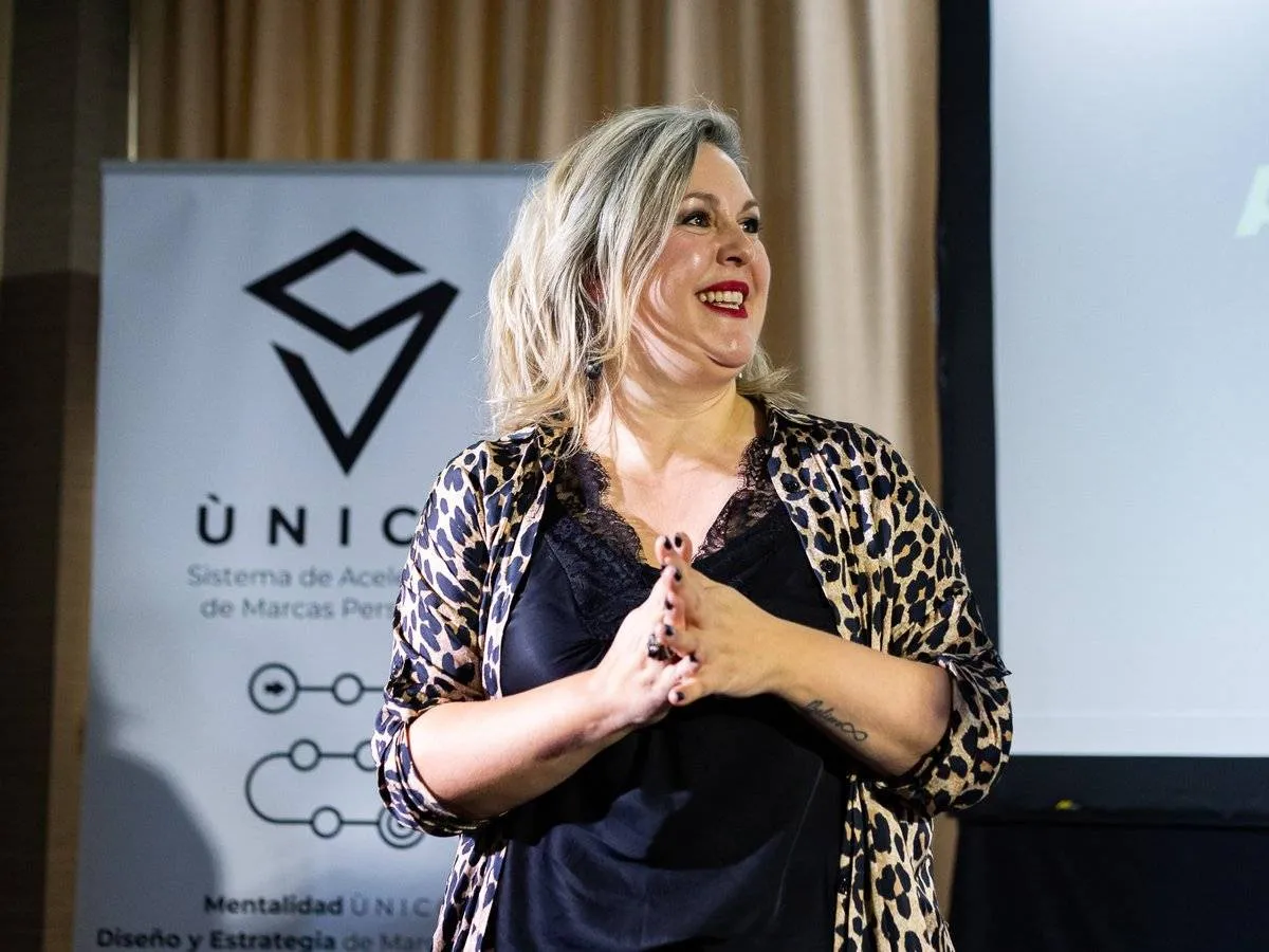 Ponente invitada hablando ante los empresarios junto al roll-up de ÚNICO